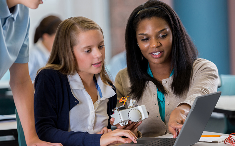 Teacher holding a Lenovo device while teaching a class