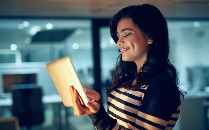 Woman smiling while using tablet device