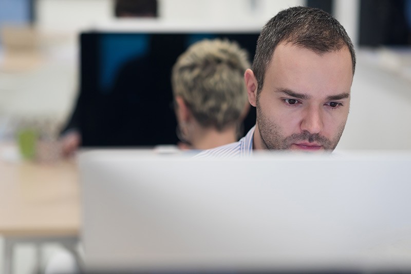 Man at his desk, concentrating and staring into computer