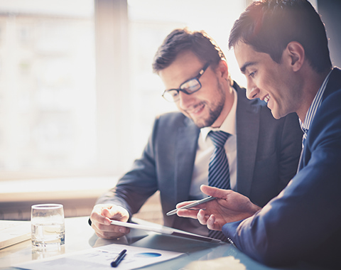 Smartly dressed men looking at a tablet