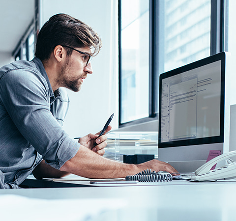 Man with glasses working on a Mac