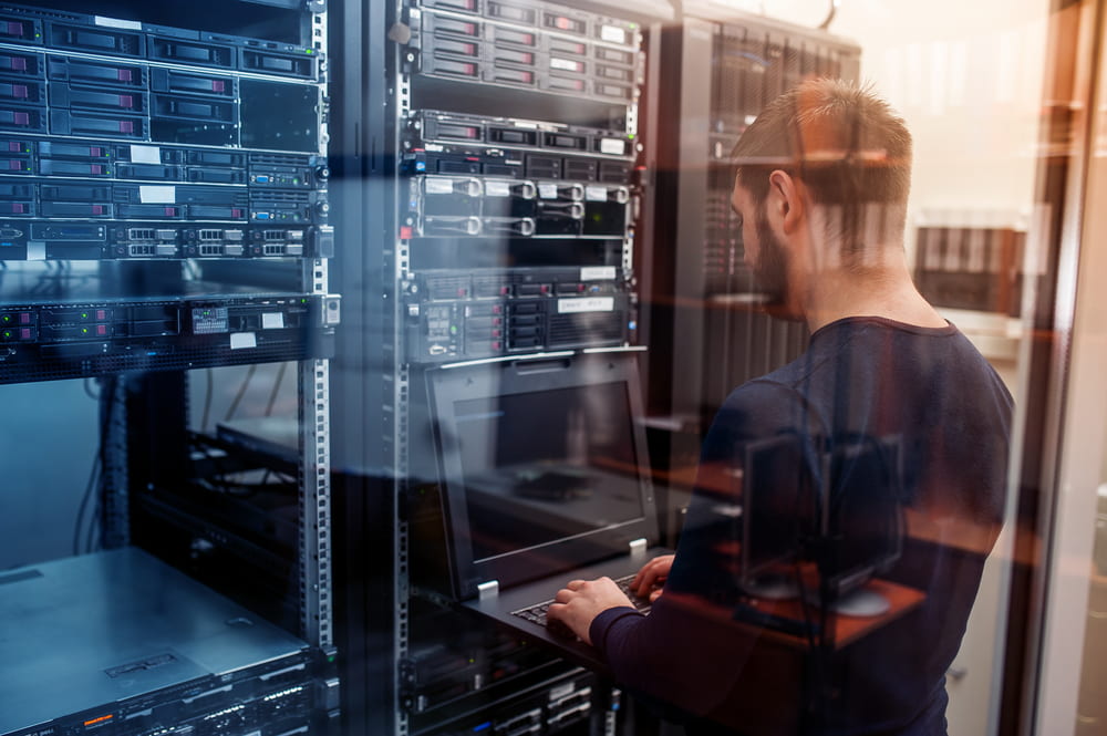 IT technician working on laptop in a data centre