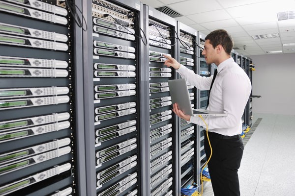 IT expert checking a server while holding a laptop in his hands