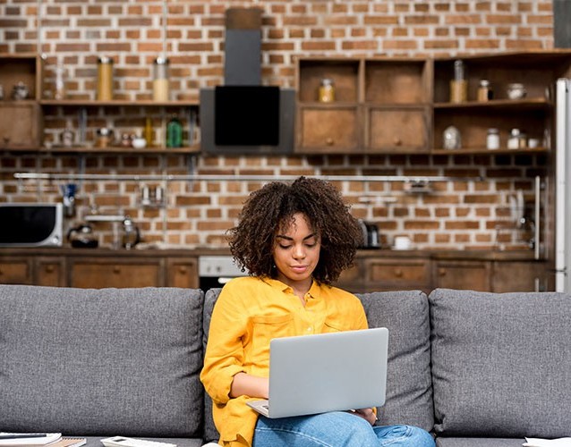 Woman working on laptop on sofa