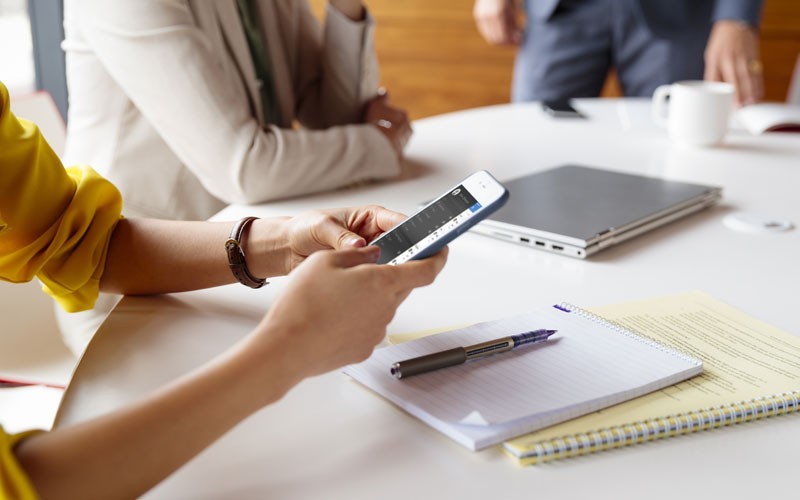 Woman in meeting working on mobile device