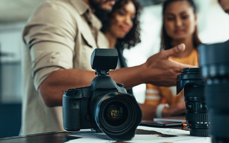 Memory that you can rely on. Group of people chatting next to a DSLR camera