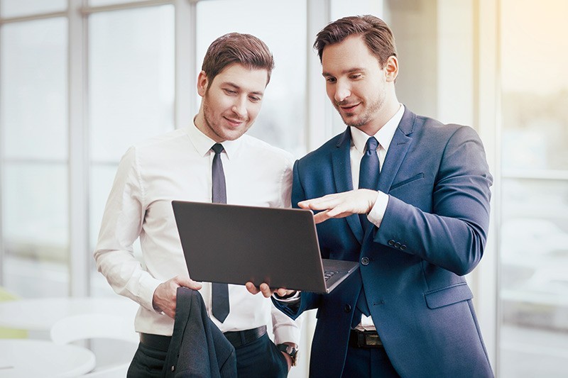 Two males looking at black laptop