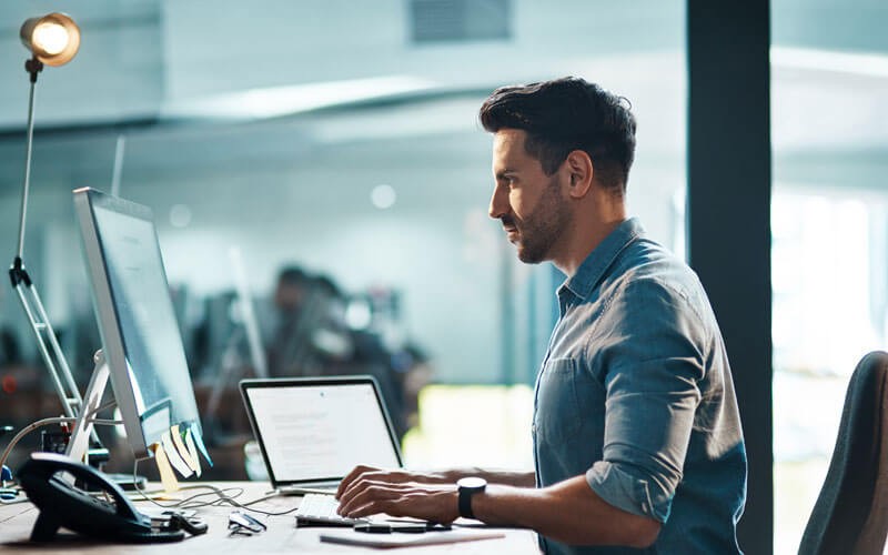 Built-in security that safeguards your business IT professional with desktop and laptop computer working in office at night