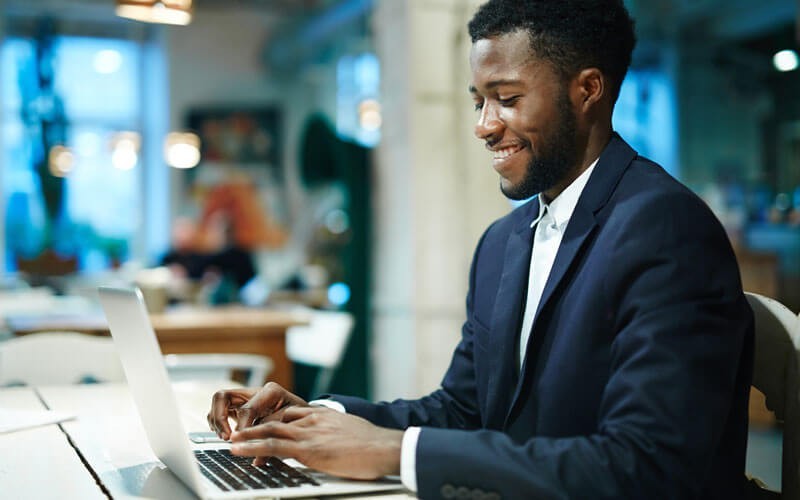 Speed the time it takes execute tasks and maintain your systems Smiling businessman on laptop computer in open office