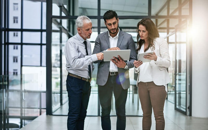 Enterprise-grade security and scalability for any environment Group of business professionals standing around tablet device in hallway