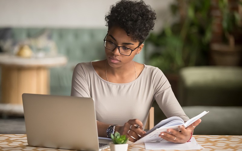 Boost SaaS performance Woman taking notes while looking at a laptop