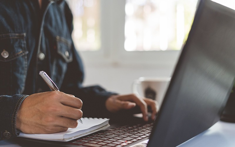 Man taking notes from a laptop device