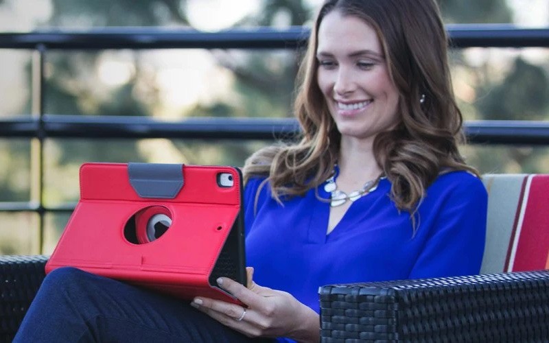 Cases designed for Apple iPad. Woman sitting on a chair while working on an iPad.