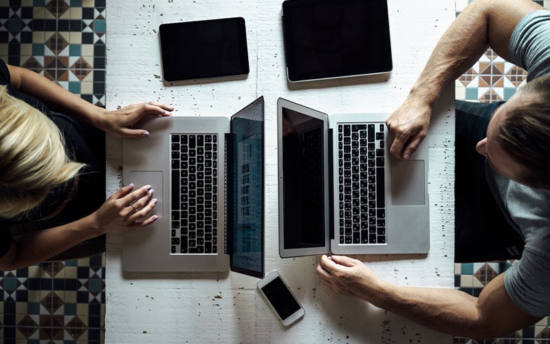 Two colleagues using laptops on a desk